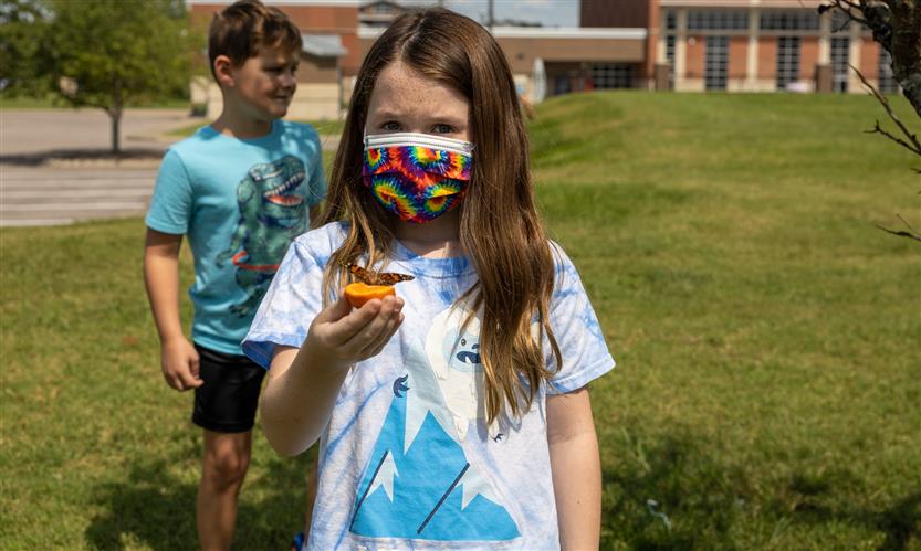 Students smile while releasing butterflies outside